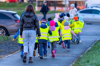 Straßenverkehrsregeln lernen Eine Gruppe von Kleinkindern in gelben reflektierenden Westen, gehen mit ihren Erzieherinnen und Erziehern einen Spaziergang machen, um die Straßenverkehrsregeln zu lernen.