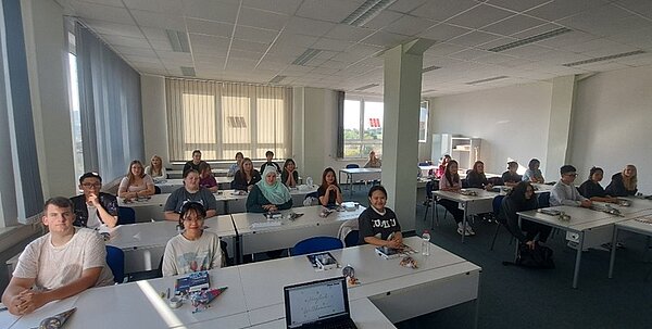 Die neuen Schülerinnen und Schüler sitzen in ihrem Klassenraum.